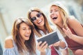 Three happy smiling female friends sharing a tablet computer Royalty Free Stock Photo