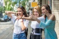 Three happy teenage girls looking something in front of them and taking a photograph on mobile phone, outdoors. Royalty Free Stock Photo