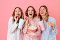 Three happy women in homewear eating pop corn and drinking soda Royalty Free Stock Photo