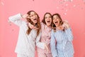 Three happy women 20s wearing leisure clothings hugging and having fun at slumber party while showing victory sign, isolated over Royalty Free Stock Photo