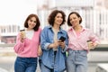 Three Happy Women With Smartphone And Takeaway Coffee Posing At Outdoor Terrace Royalty Free Stock Photo