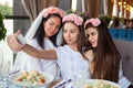 Three happy women taking selfie at hen party in cafe