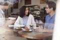 Three happy young adult friends sit talking at a coffee shop Royalty Free Stock Photo