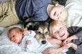 Three Happy Young Children Snuggling with Pet Dog in Bed