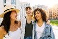 Three happy young female friends hanging out together in city street Royalty Free Stock Photo