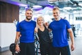 Three happy young people standing at the gym. Royalty Free Stock Photo