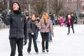 Three happy young people, woman and man. Using mobil telephones when skating at a public ice s.