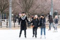 Three happy young woman skating at a public ice skating rink outdoors.