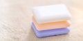 Three hard bars of soap on a pale brown towel. Side view. Copy space