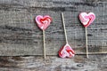 Three heart-shaped white-red lollipops on a wooden surface