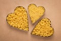 Three hearts of pasta on brown paper background. Art design. Vintage parchment. Shape of heart, symbol of love. Heap of uncooked m