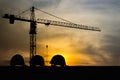 Three helmet silhouette at construction site with crane background and sunset Royalty Free Stock Photo