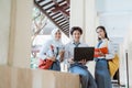 three high school students smiling at the camera while standing on a laptop computer, carrying books, and wearing a bag Royalty Free Stock Photo