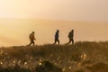 Three hikers exploring the countryside on mountain hill side at sunset beautiful orange sky in Hope Valley near Chesterfield Derby