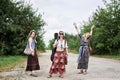 Three hippie women, wearing boho style clothes,, walking on dirt road in countryside, dancing, relaxing, having fun. Friends,