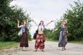 Three hippie women, wearing boho style clothes,, walking on dirt road in countryside, dancing, relaxing, having fun. Friends,