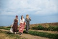 Three hippie women, wearing boho style clothes, walking on dirt road on green field, having fun. Female friends, traveling