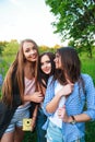 Three hipsters girls blonde and brunette taking self portrait on polaroid camera and smiling outdoor. Girls having fun together Royalty Free Stock Photo