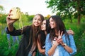 Three hipsters girls blonde and brunette taking self portrait on polaroid camera and smiling outdoor. Girls having fun together Royalty Free Stock Photo