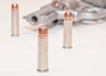 Three hollow point bullets with a loaded revolver in the background Royalty Free Stock Photo