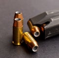 Three hollow point bullets next to a black pistol magazine