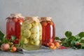 Three canned apple and cherry compote in large glass jars on gray table.