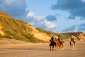 Three horses and riders approach from distance with leading lines and patterns of car tracks