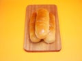 Three Hot Dog Buns on a wooden cutting board. isolated on a yellow background. Royalty Free Stock Photo