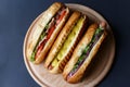 Three hot dogs lying on the wooden plate