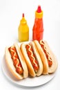 Three hotdogs with mustard and ketchup bottles