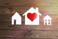 Three houses made of paper with a heart shape on a wooden background. concept of housing, family