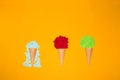 three ice cream cones, one with a green paper ball, another with red, and a third with melted blue