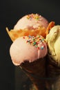 Three Ice Cream in waffle Cone with scoop of Pink Fruit ice cream and Confetti in glass isolated on Dark blue Background. Party, d Royalty Free Stock Photo