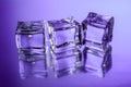 Three ice cubes on glass surface with violet gradient background Royalty Free Stock Photo