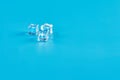 Three ice cubes are lying on the table on a blue background Royalty Free Stock Photo