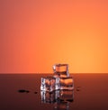 Three ice cubes and water on orange background Royalty Free Stock Photo