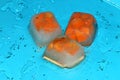 three ice cubes in which the carrot is on a glass of blue background Royalty Free Stock Photo