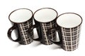 Three identical big tall dark brown coffee cups with simple lines design
