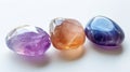 Three identical-sized gemstones, Amethyst, Rose Quartz, and Moonstone, aligned side by side, each displaying their