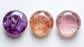 Three identical-sized gemstones, Amethyst, Rose Quartz, and Moonstone, aligned side by side, each displaying their