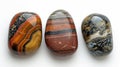 Three identical-sized stones, Tiger's Eye, Jasper, and Obsidian, aligned side by side, revealing their unique