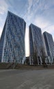 Three identical skyscrapers of a futuristic shape are built in a row. An example of modern architecture. Many windows are repeated