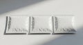 Three blank white packaging pouches lined up with diagonal shadows casting across them Royalty Free Stock Photo