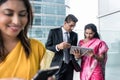 Three Indian business people using modern devices indoors