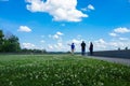 Three Indian friends are walking in a park with flowers and blue sky.