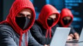 Three individuals in red hoodies and masks work on laptops in dark environment, creating tense atmosphere of cyber activity and