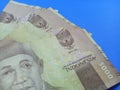 three Indonesian currency notes worth five thousand rupiahs lined up on a blue background