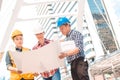 Three Industrial engineer wear safety helmet engineering working and talking with drawings inspection