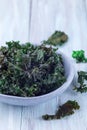 Three ingredient baked green kale chips with sea salt and olive oil, in gray bowl, vertical, copy space