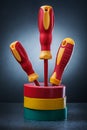 Three insulated electrical screwdrivers standing in stack of rolls insulation tapes on black background Royalty Free Stock Photo